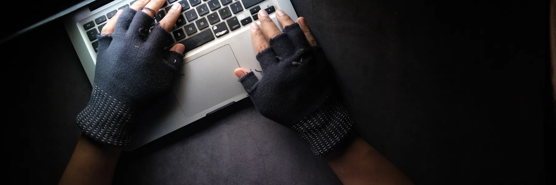 Hacker mit Handschuhen auf einer Notebooktastatur
